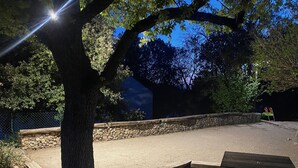 A paved area with a stone wall, trees, and a bench. - Le Petit Paradis Provençal (Cigales 2) (Allemagne en Provence)