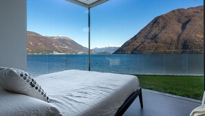 A bedroom with a large window overlooking a lake and mountains. - Marvelous Lake Destination eco-friendly villa (Brienno)