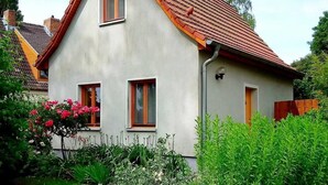 Ein zweistöckiges Haus mit rotem Ziegeldach, zwei Fenstern und einer kleinen angebauten Garage.