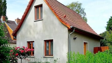 Ein zweistöckiges Haus mit rotem Ziegeldach, zwei Fenstern und einer kleinen angebauten Garage.