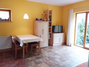 A room with a dining table, chairs, a cabinet with a TV, and a window with a view.