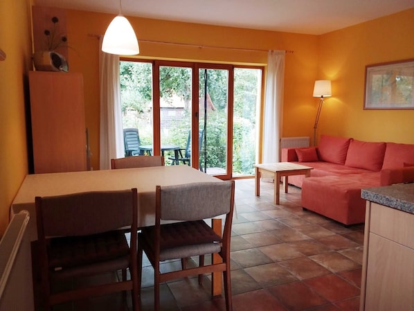 A dining area with a table and chairs, a sofa, and a lamp.