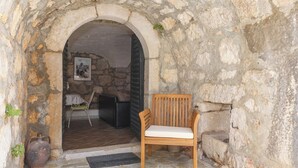 An arched stone doorway leading to a room with a wooden chair and a table. - Unique mediterranean stone house with pool (Grižane)