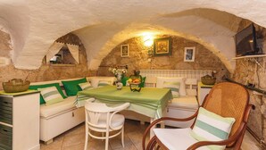 A cozy dining area with a table set for two, a sofa, and a wicker chair. - Unique mediterranean stone house with pool (Grižane)