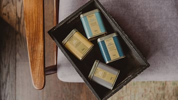 A box containing four small tins with labels, placed on a chair.
