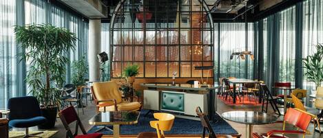 A modern interior with a central seating area, large windows, and a variety of chairs and tables.