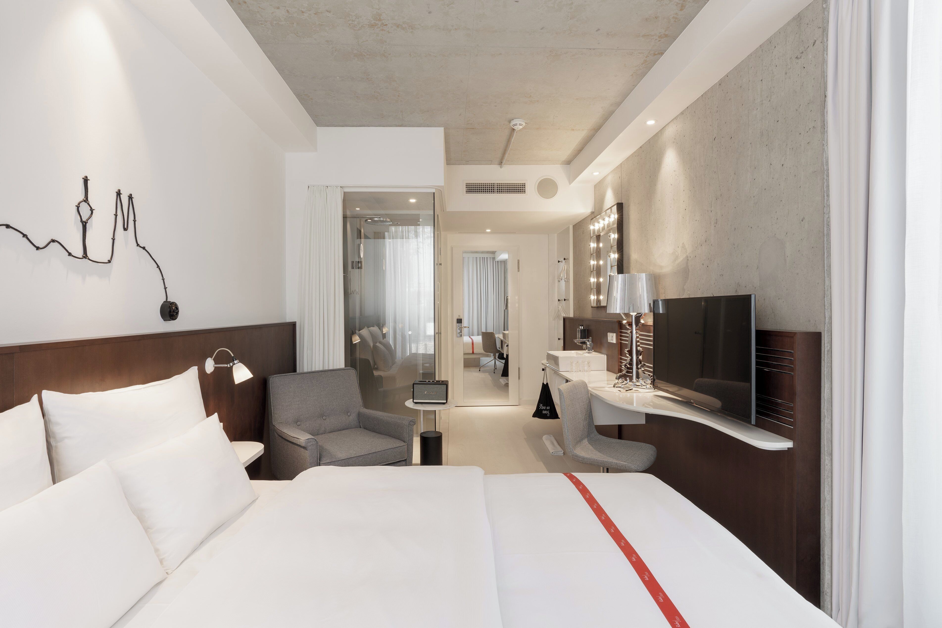 Habitación de hotel con una cama grande, un escritorio con televisor, una silla, un espejo y una obra de arte en la pared.