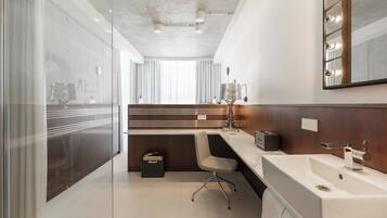 A modern bathroom with a large mirror, vanity, and a bathtub.