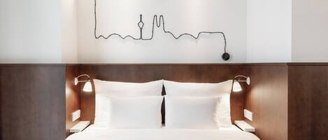 Una cama bien hecha con cabecera, dos lámparas de noche y una obra de arte en la pared.