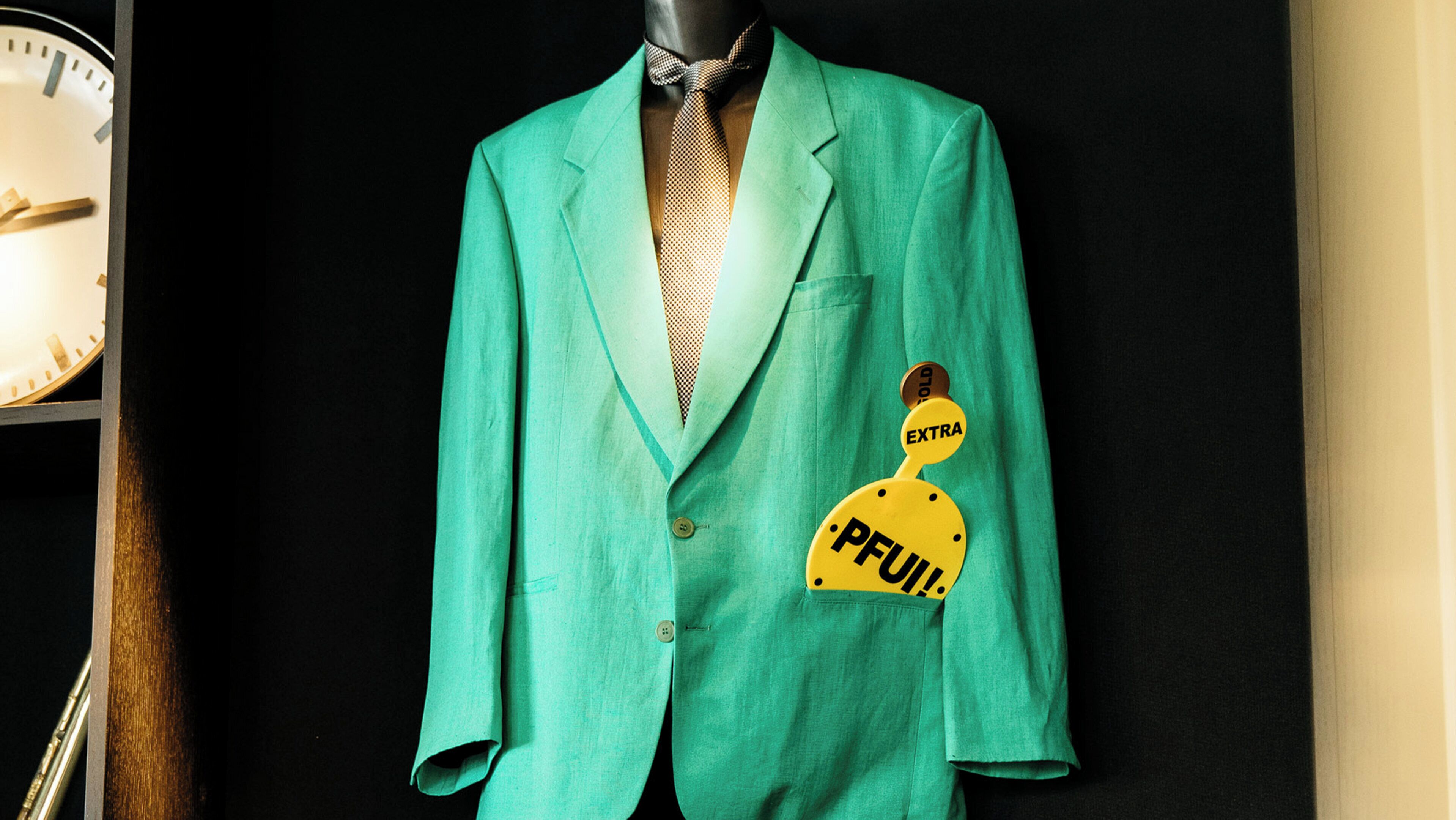 A mannequin dressed in a teal suit with a patterned tie and a yellow pocket square labeled 'FULL.'