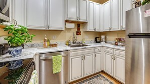 A modern kitchen with white cabinets, stainless steel appliances, and a marble countertop.