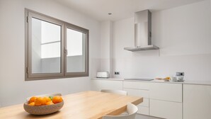 Eine moderne Küche mit weißen Schränken, einem Holztisch und einer Schüssel Orangen.