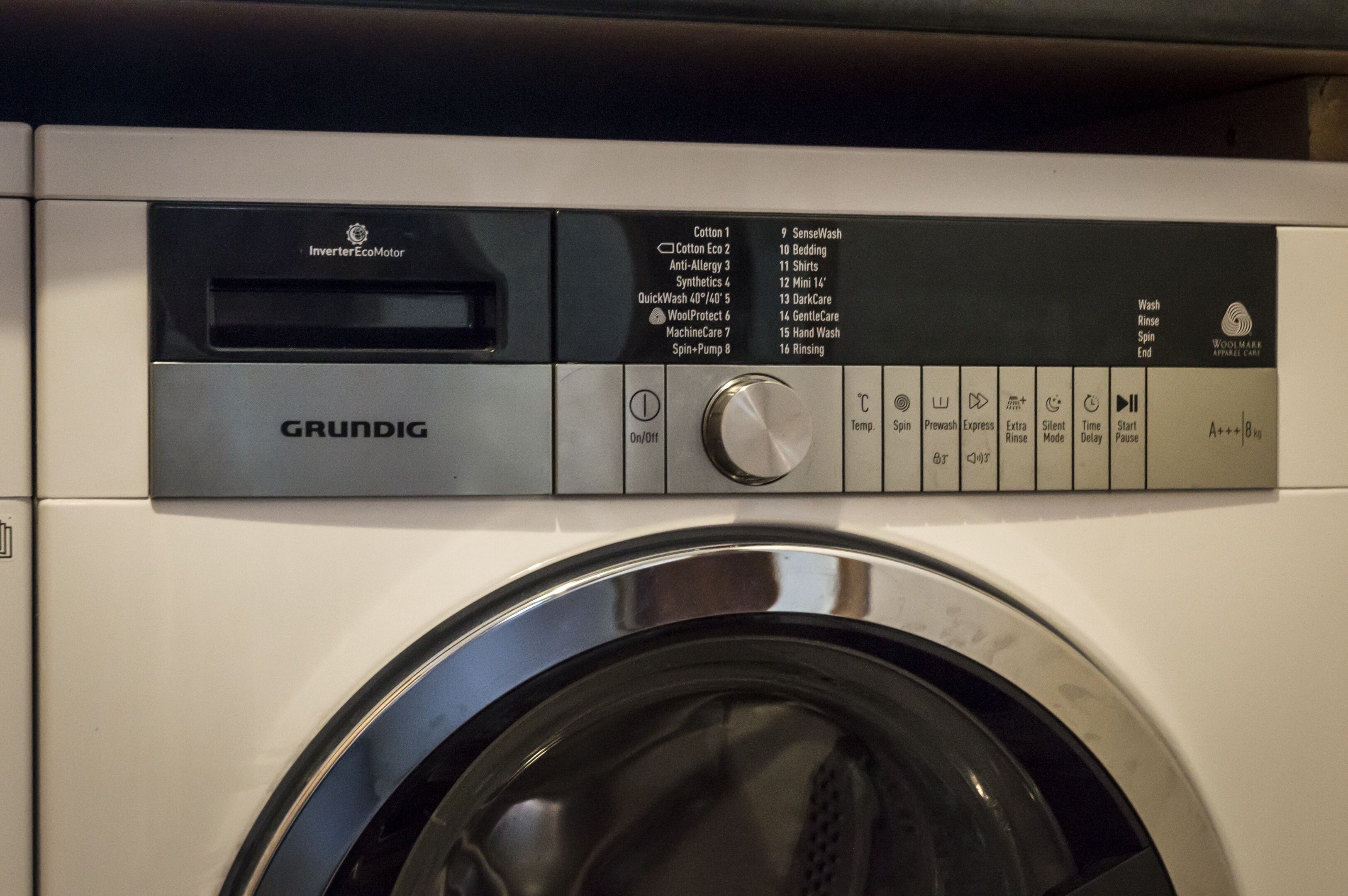 A washing machine with a control panel displaying various wash cycles and settings.