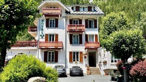 Ein Hotel mit weißer Fassade, roten Balkonen und einer Bergkulisse im Hintergrund.