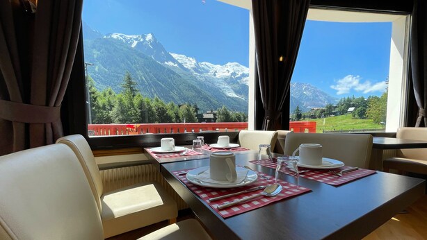 Comedor con una mesa para dos, vista a la montaña y barandal rojo.