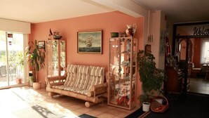 A cozy living room with a striped sofa, a glass cabinet with decorative items, and a large window allowing natural light. - Hotel Bertramshof (Wismar)