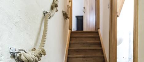 A wooden staircase with a rope tied to a metal bracket on the wall.
