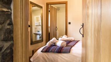 A hotel room with a bed, a mirror, a wooden wardrobe, and a bathroom visible through an open door.