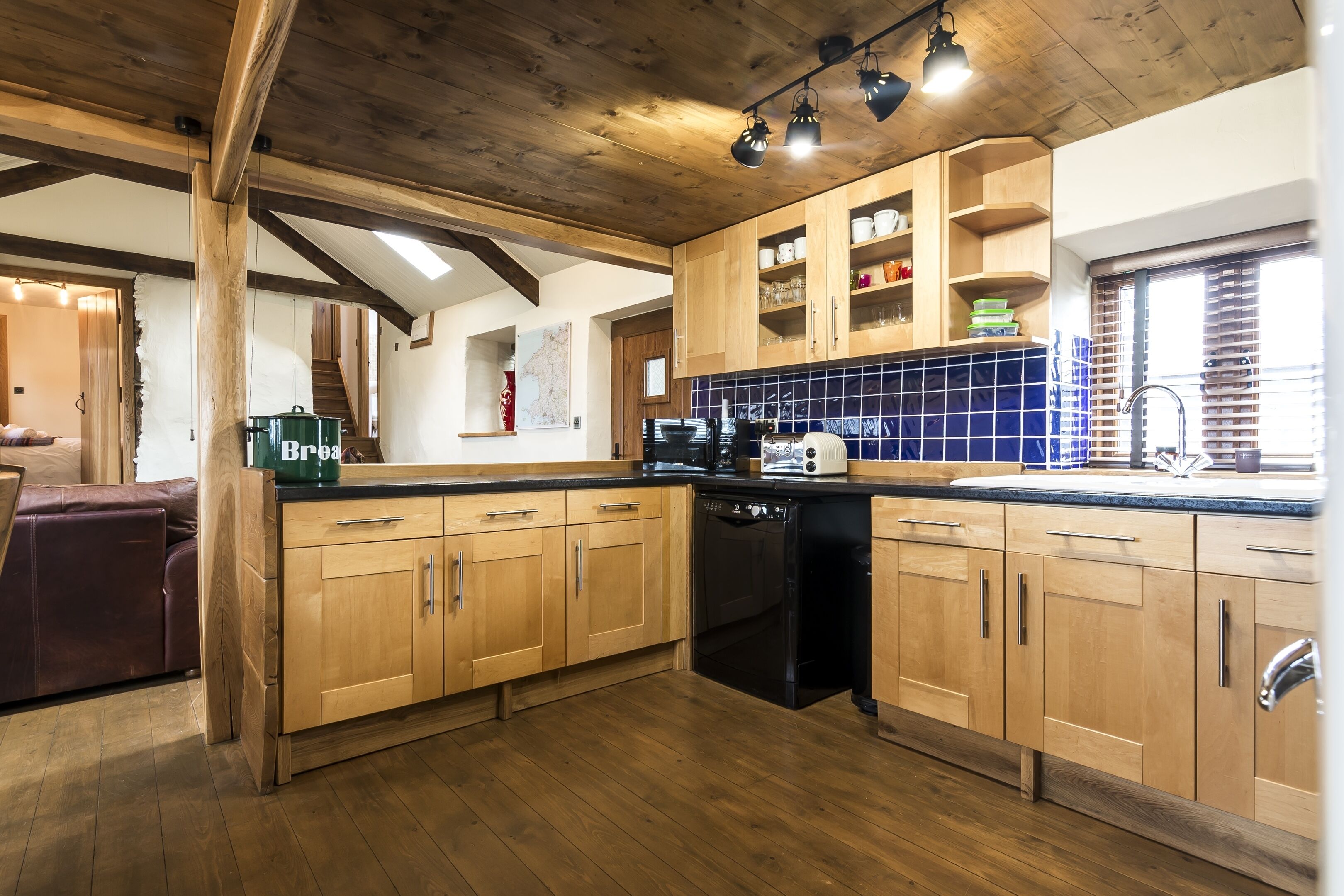A kitchen with wooden cabinets, a dishwasher, and a blue-tiled backsplash.