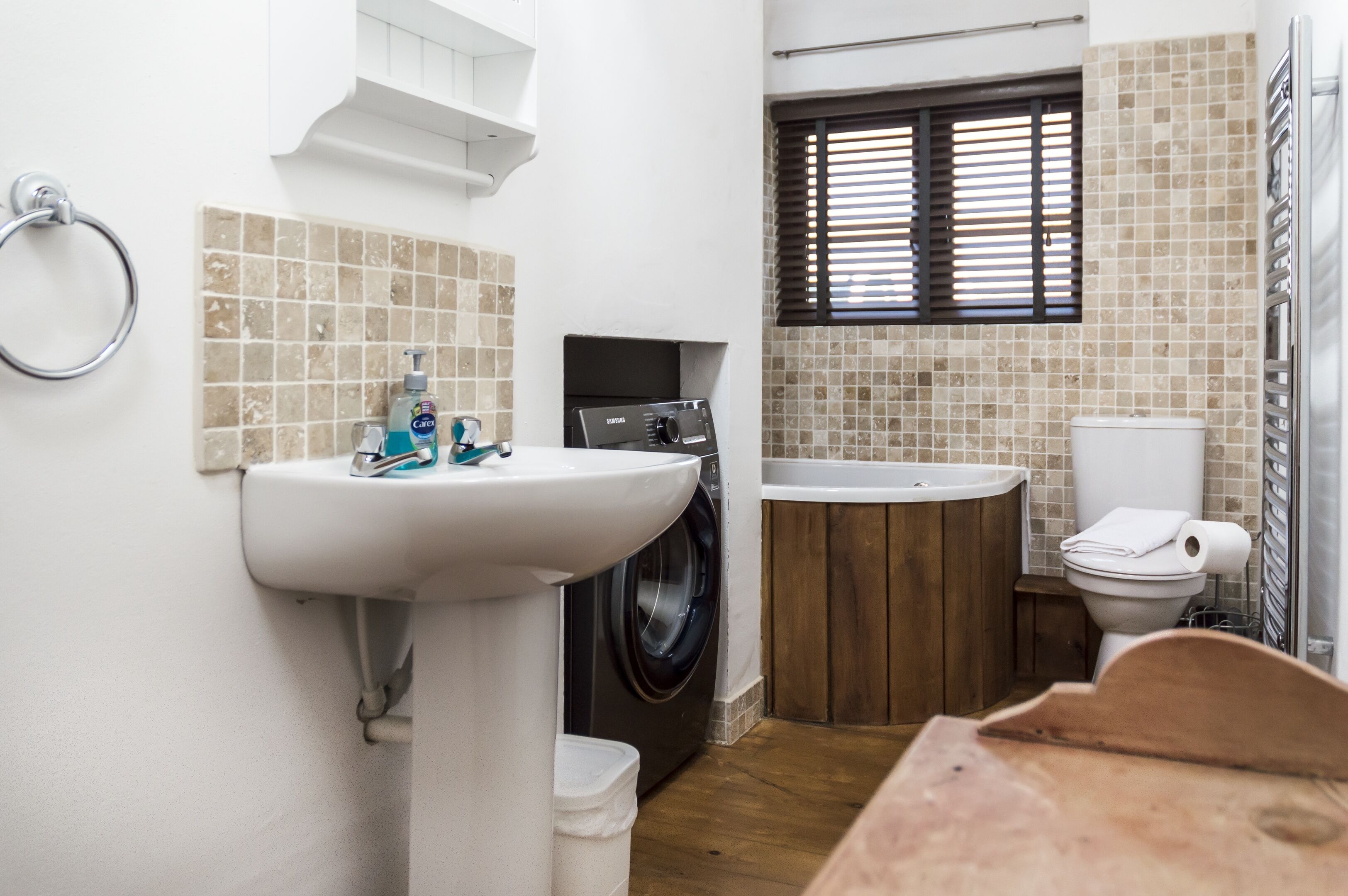 Ein kleines Badezimmer mit Waschbecken, Waschmaschine, Badewanne und Toilette.