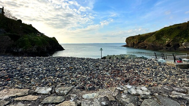 Une plage rocheuse avec un sentier pavé de pierres menant à une jetée.