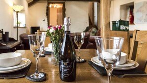 Une table à manger dressée avec des verres à vin, une bouteille de vin et un vase rempli de fleurs.