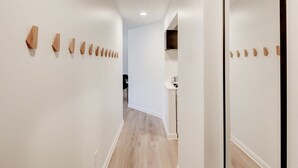 Un pasillo con decoración de madera en las paredes, una zona de cocina y suelo de madera.
