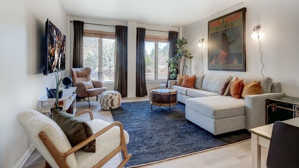 Una sala de estar moderna con un sofá, sillones, una mesa de centro y una alfombra.