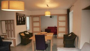 Un coin repas avec une table et des chaises, un canapé rouge et un tableau au mur.