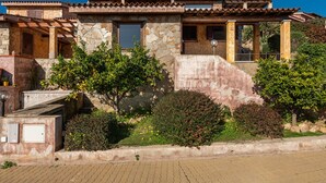 A stone building with a tiled roof, a covered porch, and a landscaped garden.