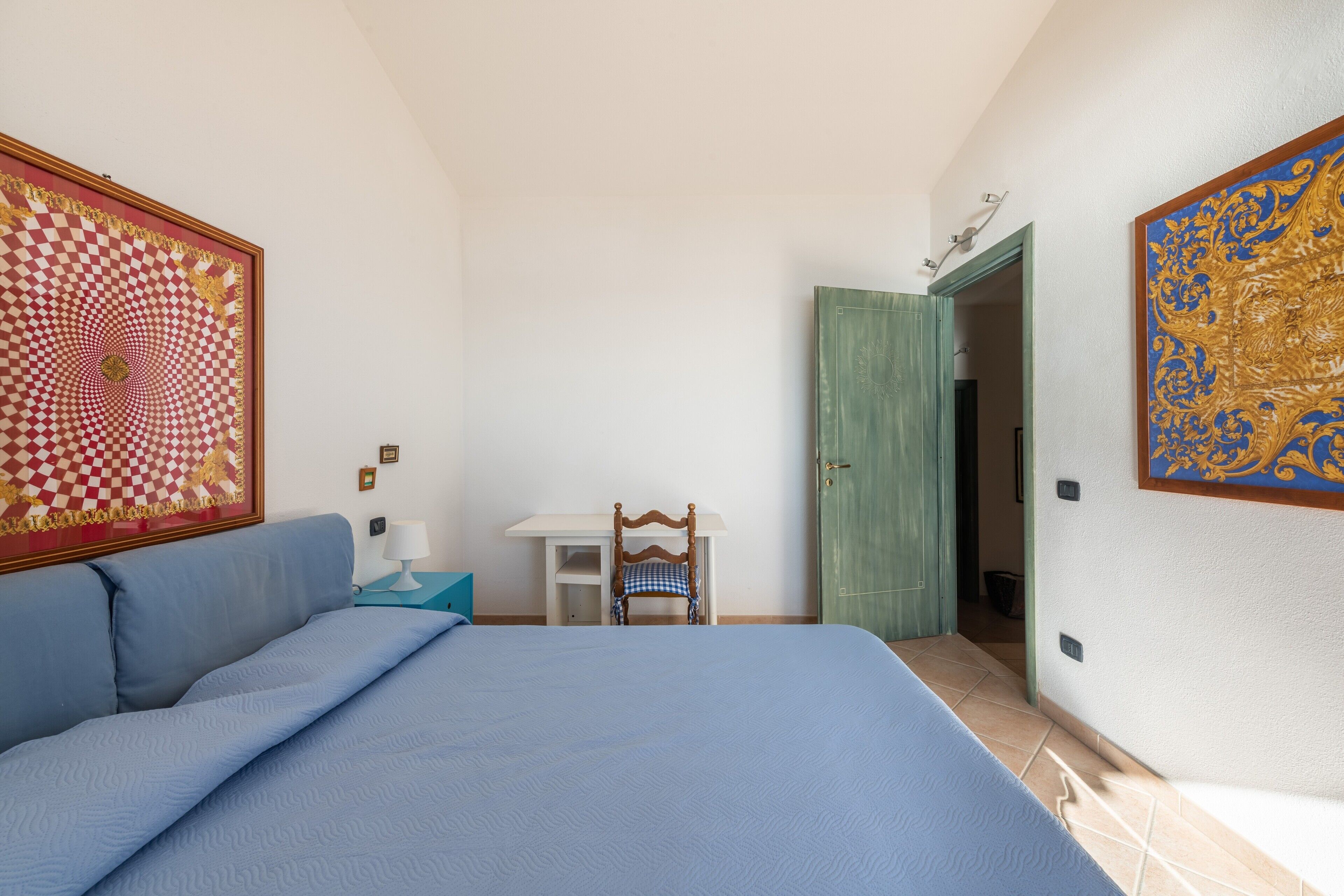 Une chambre à coucher avec un lit, une chaise, un bureau et une porte.