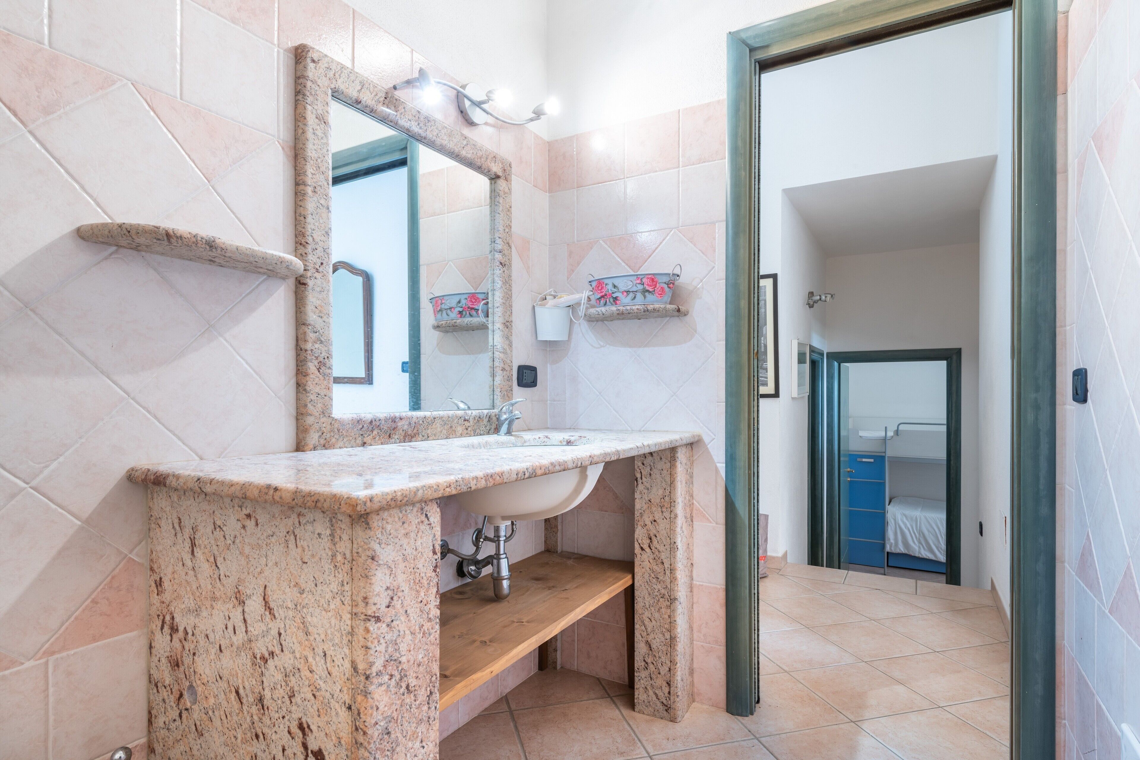 Une salle de bain avec un comptoir en granit, un lavabo, un miroir et un espace douche.