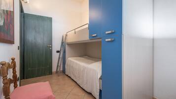 A room with a bunk bed, a wooden chair, a door, and a ladder.