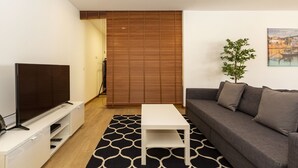 Un salon moderne avec un téléviseur à écran plat, une table basse blanche, un canapé gris et un tapis à motifs.