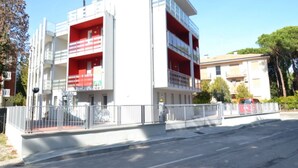 A modern multi-story building with balconies and a gated entrance. - Modern flat in central location (Rosolina Mare)