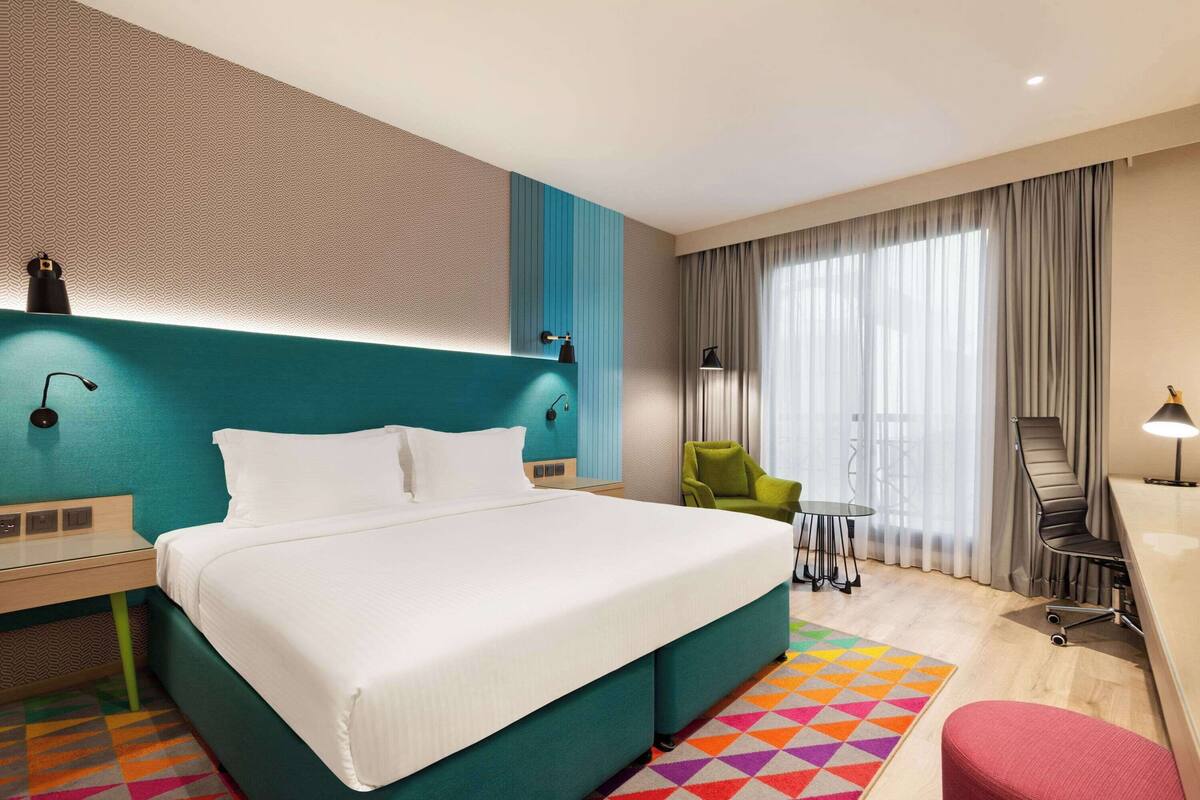 Una habitación de hotel con una cama grande, un escritorio, una silla y una mesita.