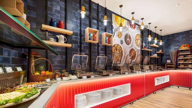 A buffet area with a red counter, various food items, and decorative wall art. - La Quinta by Wyndham Dubai Jumeirah (Dubai)