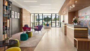 A modern lobby with a reception desk, colorful seating, and large windows offering views of the city. - La Quinta by Wyndham Dubai Jumeirah (Dubai)