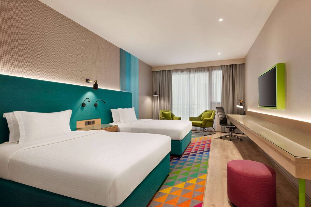Una habitación de hotel con dos camas, un escritorio, una silla y un televisor.