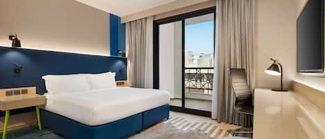 Une chambre d’hôtel avec un lit, un bureau, une chaise, une télévision et un balcon avec vue.