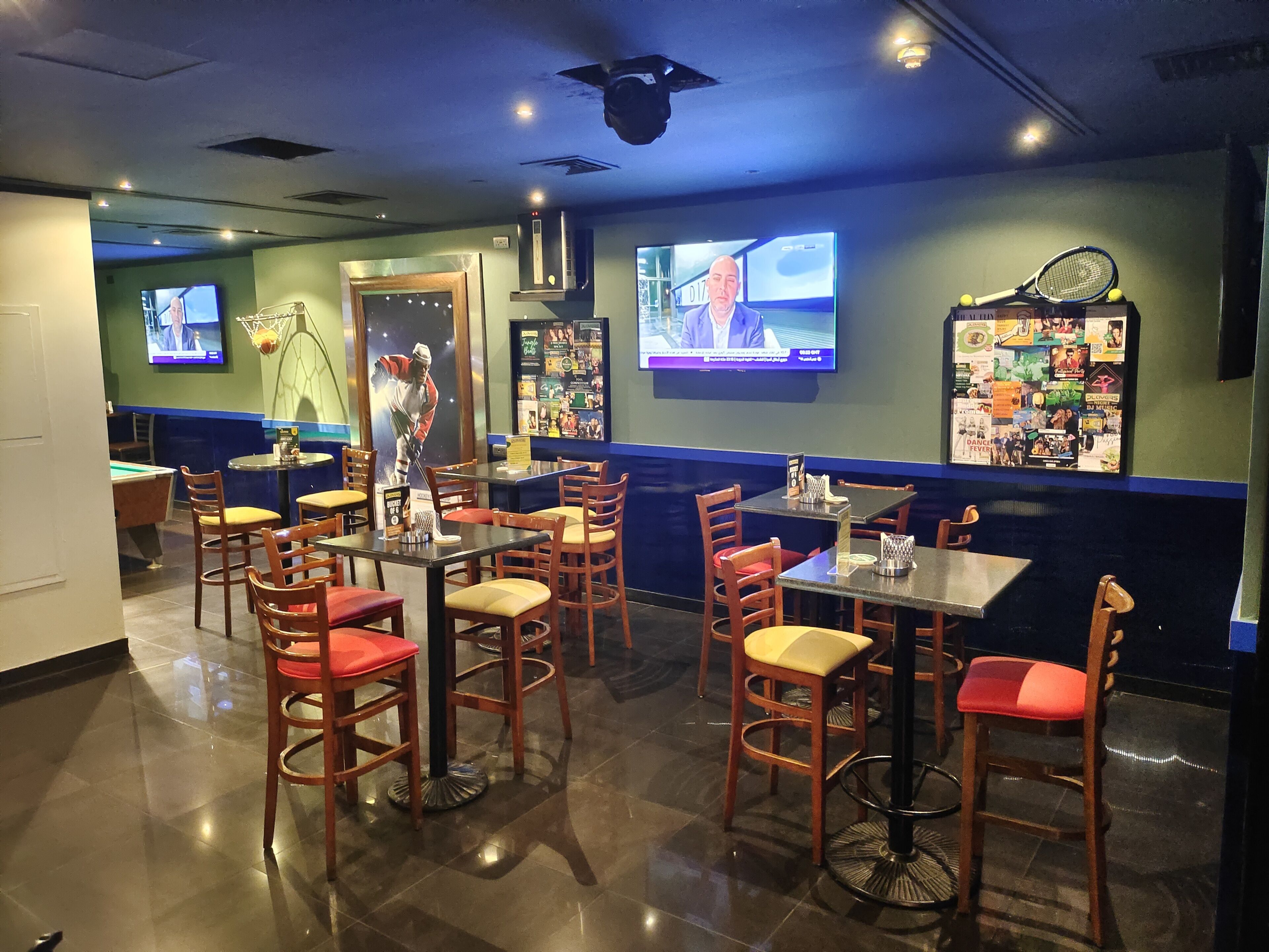 A restaurant with multiple tables and chairs, a pool table, and sports memorabilia on the walls.