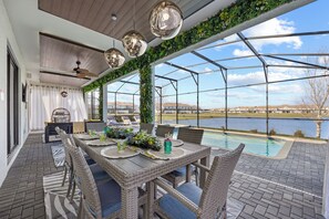 A covered patio with a dining table, chairs, and a view of a lake.