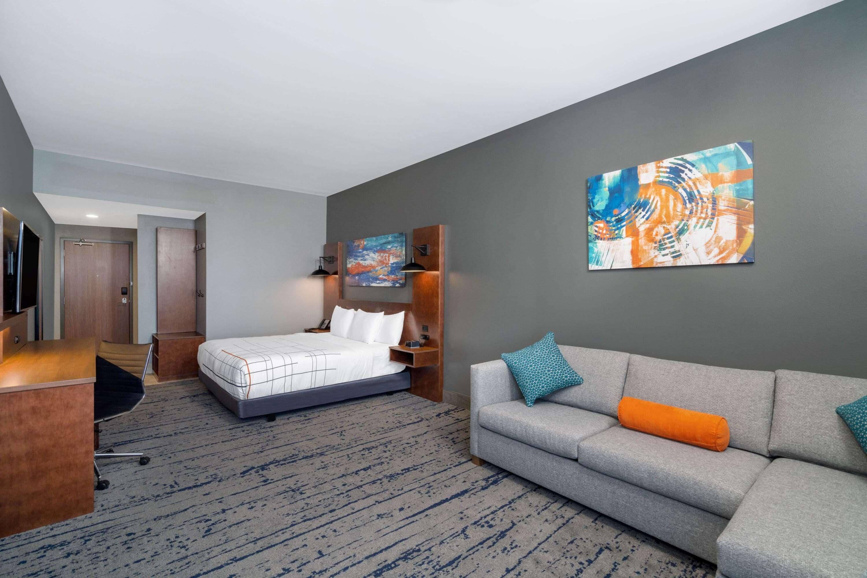 Una camera d'albergo con un letto, un divano, una scrivania e un quadro appeso al muro.