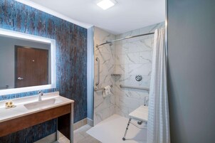 Un baño moderno con cabina de ducha de mármol, tocador de madera y un espejo grande.