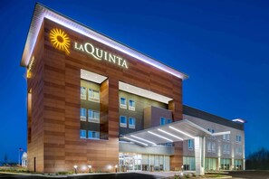 Un hotel La Quinta con un diseño moderno, que presenta un llamativo logo de sol, varias ventanas y una entrada cubierta.