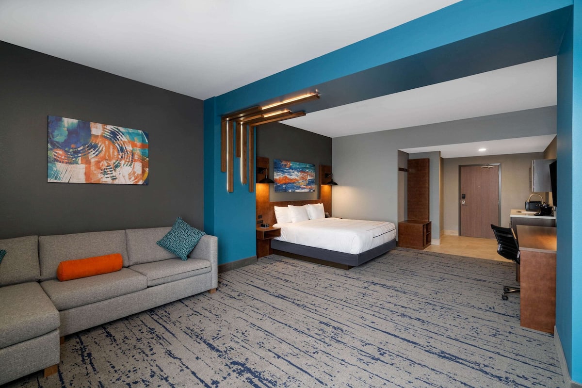 Une chambre d’hôtel avec un lit, un canapé, un bureau et un tableau au mur.