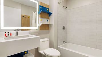 A modern bathroom with a white sink, toilet, and bathtub. There is a mirror above the sink and a towel rack below it.