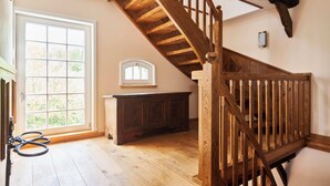 Una escalera de madera con vistas a un jardín a través de un ventanal grande.
