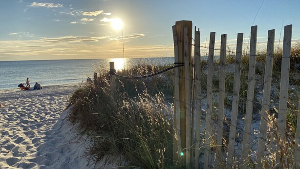 A sandy beach with a wooden fence and a clear sky.