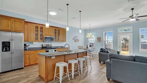 A modern kitchen with wooden cabinets, a stainless steel refrigerator, and a central island with bar stools.
